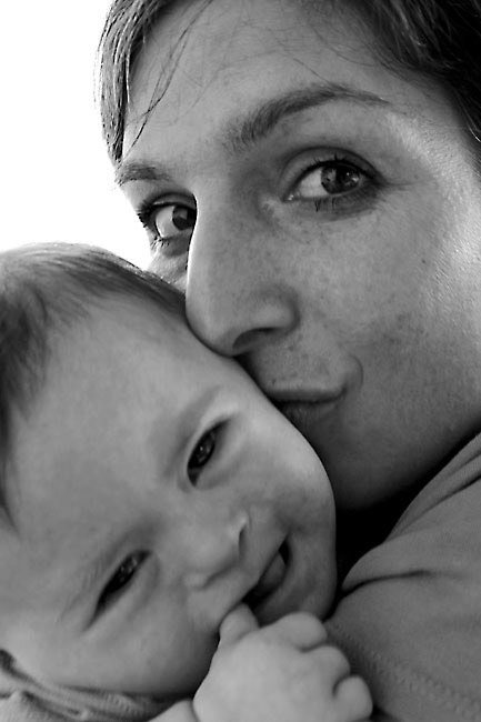 Schwarz-weiß Bild von Mutter mit Baby mit Down-Syndrom. Mutter (ich) küsst das Kind(Sonea) und schaut in die Kamera.